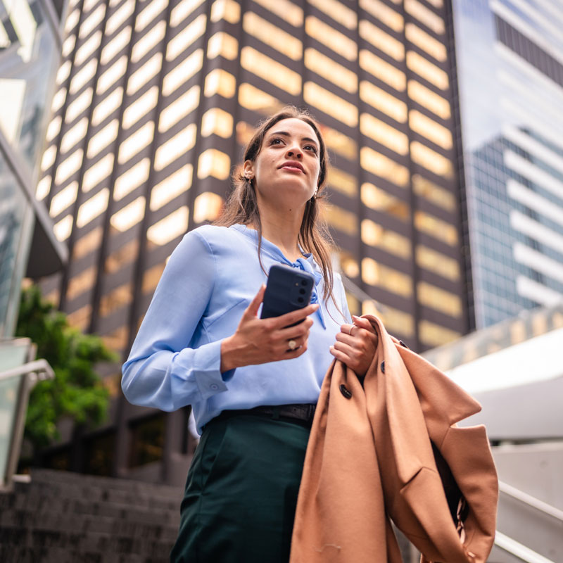 Businesswoman standing in the city holding a mobile phone