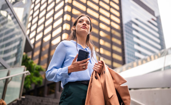 Businesswoman standing in the city holding a mobile phone
