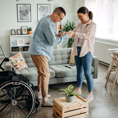 woman helping man standup from wheelchair