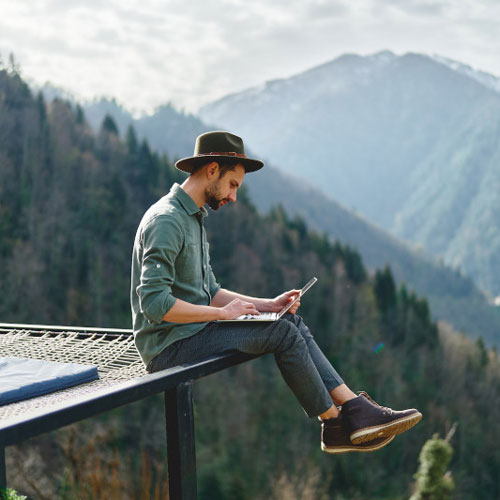 man sitting outdoors looking at laptop