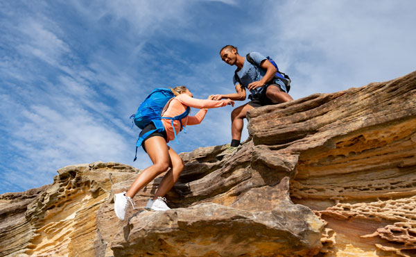 man helping woman while hiking