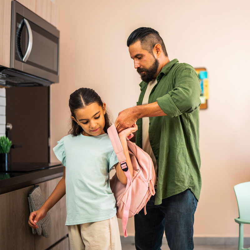 father helping daughter get ready for school