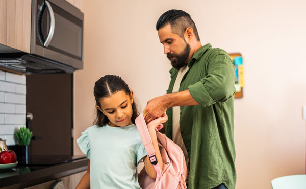 father helping daughter get ready for school